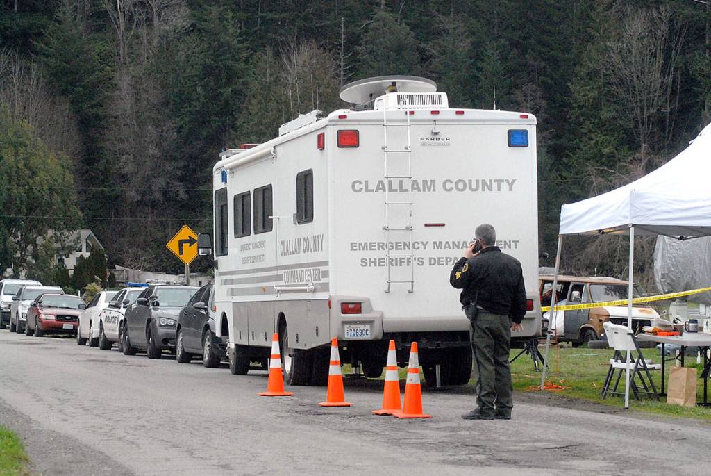 Keith Thorpe/Peninsula Daily News                                Sgt. John Hollis of the Clallam County Sheriffs Office talks on his phone outside an emergency command center set up on Lower Elwha Road west of Port Angeles on Thursday after a suspect was arrested Thursday morning in connection with a triple homicide last December.
