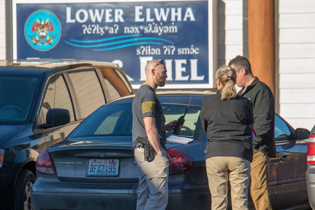 Oficials from the U.S. Marshals Service and Clallam County Sheriffs Office talk outside the Lower Elwha Food and Fuel where Ryan Ward was arrested. (Jesse Major/Peninsula Daily News)
