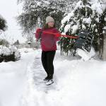 Caroline Proulx, owner of Five Sea Suns Bed and Breakfast in Port Angeles, shovels snow from the sidewalk in front of her business in Port Angeles on Saturday morning. (Keith Thorpe/Peninsula Daily News)