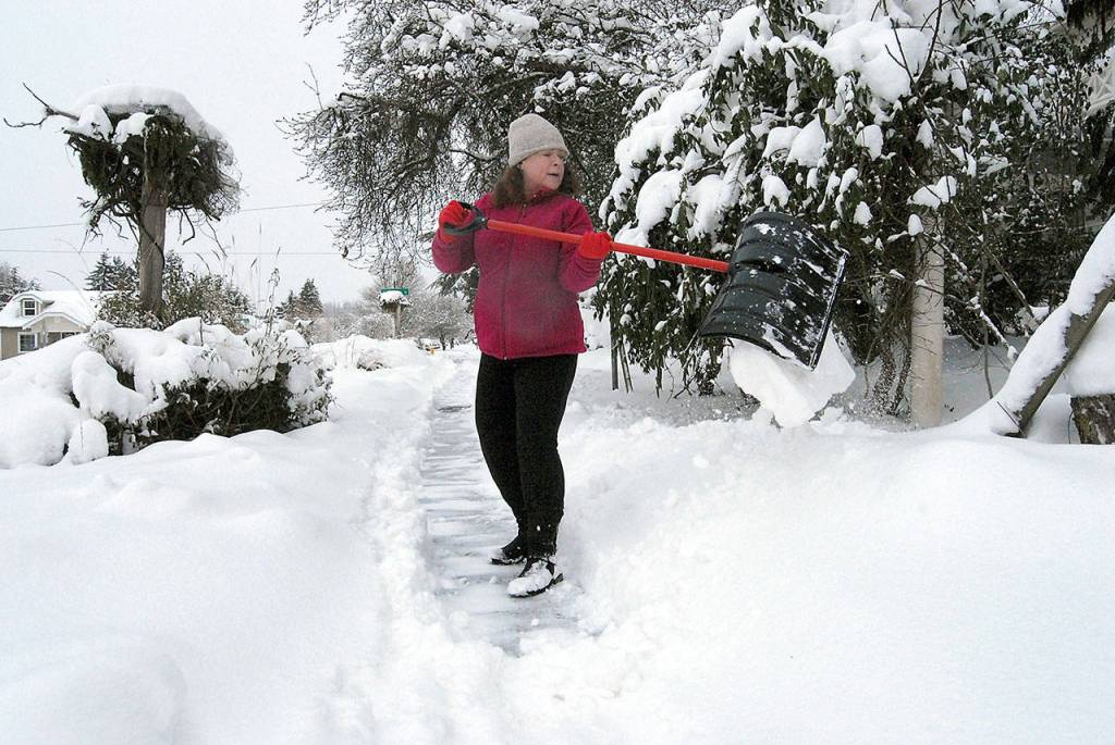 Caroline Proulx, owner of Five Sea Suns Bed and Breakfast in Port Angeles, shovels snow from the sidewalk in front of her business in Port Angeles on Saturday morning. (Keith Thorpe/Peninsula Daily News)