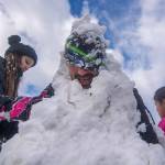 Bruce Delgado braves the cold as kids cover him with snow during a community snowball fight in Port Angeles on Sunday. (Jesse Major/Peninsula Daily News)