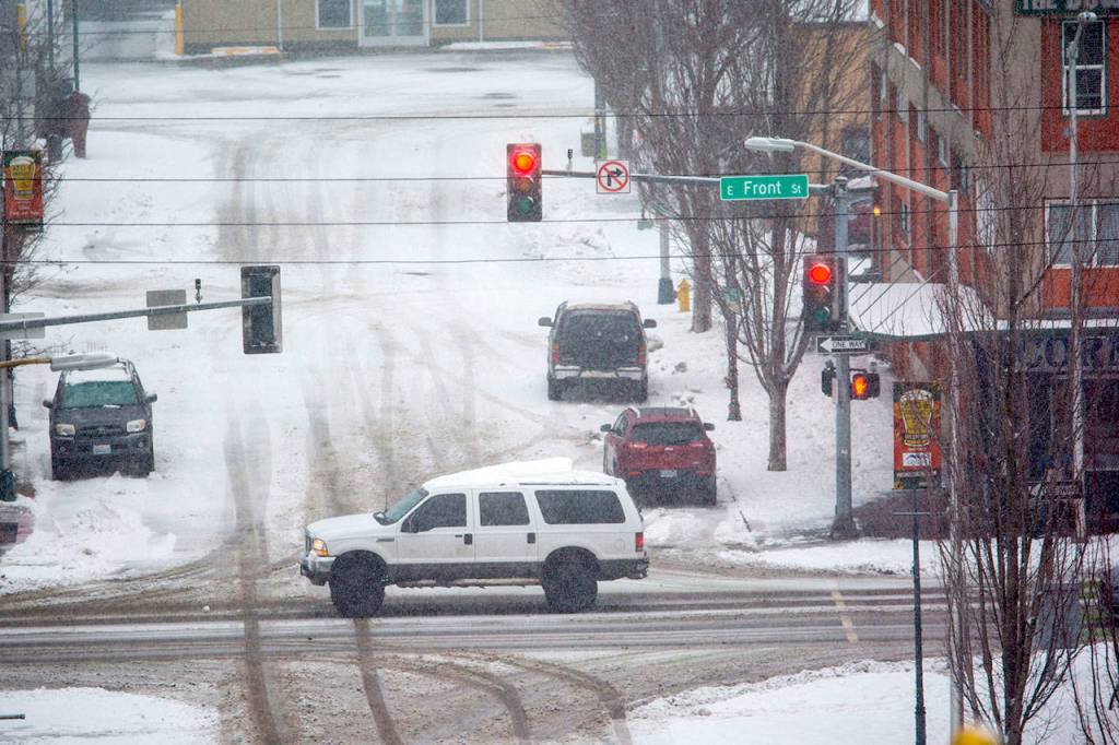 Traffic makes its way through downtown Port Angeles as snow begins to fall Monday afternoon. (Jesse Major/Peninsula Daily News)