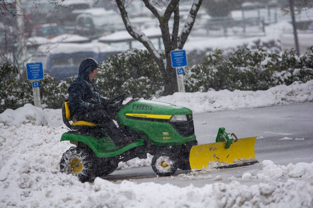 A man plows in front of the Clallam County Courthouse as snow begins to fall Monday afternoon. (Jesse Major/Peninsula Daily News)