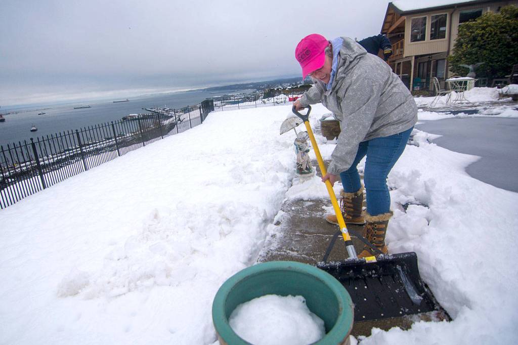 Laura Knowles clears snow at the home of a longtime Port Angeles coach while he recoveres from surgery in Seattle Tuesday. (Jesse Major/Peninsula Daily News)