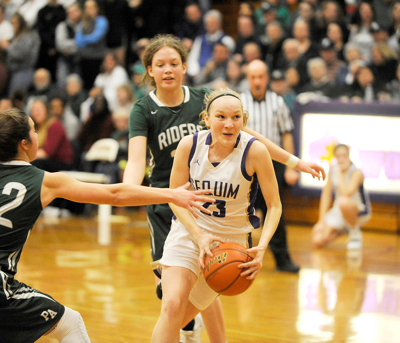 Michael Dashiell/Olympic Peninsula News Group Sequims Melissa Porter, center, splits the defense of Port Angeles Madison Cooke, back, and Eve Burke, left, during a Jan. 31 game in Sequim. The Wolves and the Riders meet for the third time this season today in a loser-out contest at the Class 2A state tournament at the Yakima SunDome.