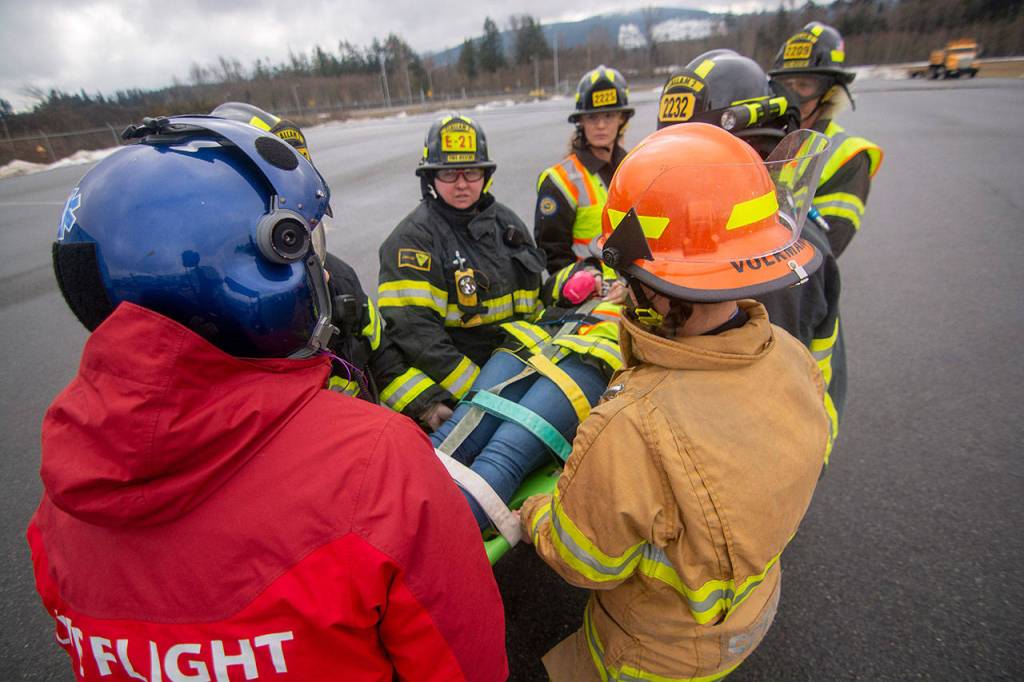 Firefighters carry a mock patient to Life Flight Networks helicopter during the training session. (Jesse Major/Peninsula Daily News)
