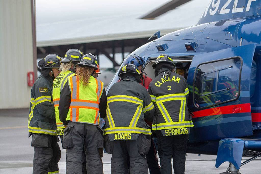 Firefighters load a mock patient into Life Flight Networks helicopter. (Jesse Major/Peninsula Daily News)