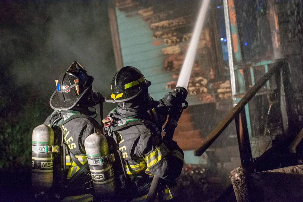 Firefighters from the Port Angeles Fire Department put water on the fire at 409 S. Valley Street in Port Angeles on Wednesday night. (Jesse Major/Peninsula Daily News)