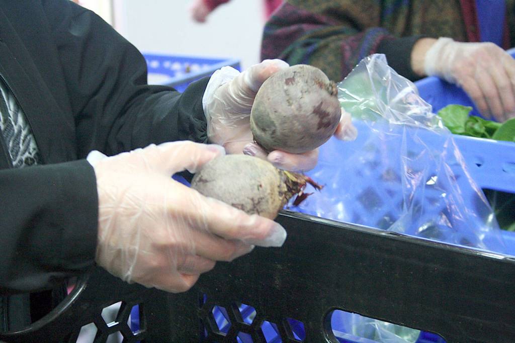 Sandra Largaespada of Food Lifeline, a nonprofit organization based in Seattle, asks a Tri-Area Food Bank client if they want beets. The food bank preferred to keep their clients anonymous. (Brian McLean/Peninsula Daily News)