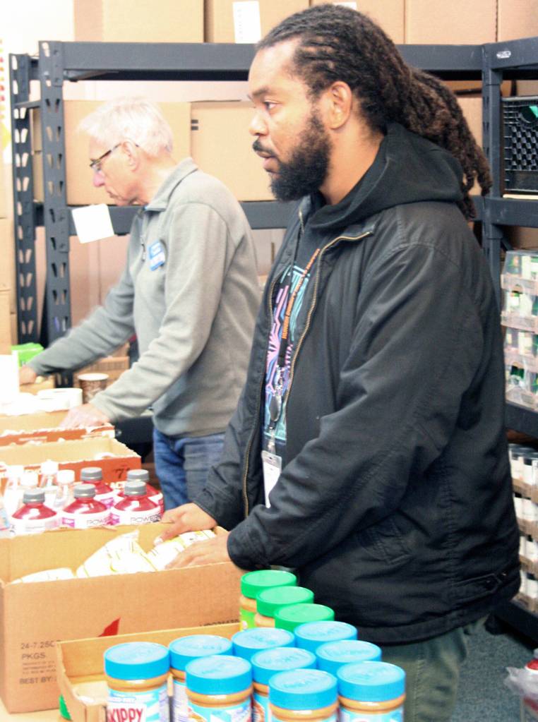 Clark Gerstenberger, left, and Gregory Whiting work with clients on Wednesday at the Tri-Area Food Bank in Port Hadlock. Whiting is the director of equity and inclusion at Food Lifeline, a nonprofit organization based in Seattle which distributes 50 million pounds per year to different agencies in western Washington. (Brian McLean/Peninsula Daily News)