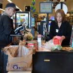 Kathy Johnson, a checker at Sequim QFC, helps Jack Guinn purchase his groceries on March 18. Starting Monday, the store will no longer offer plastic bags at checkout stands to customers. (Matthew Nash/Olympic Peninsula News Group)