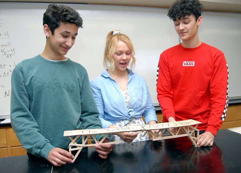 Leo Ahlburg, left, Christine Beirne and Mauritz Ahlburg, right, display their broken bridge, which held 202 pounds, before splintering. Their bridge was an unofficial entry, but still finished second in efficiency. (Keith Thorpe/Peninsula Daily News)