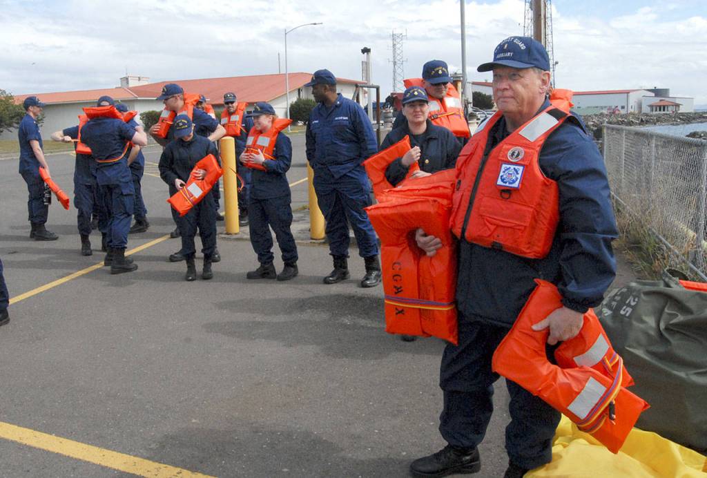 Jim Armstrong of the U.S. Coast Guard Auxillary Flotilla 44, right, assists with handing out life jackets to participants the tsunami evacuation drill. (Keith Thorpe/Peninsula Daily News)