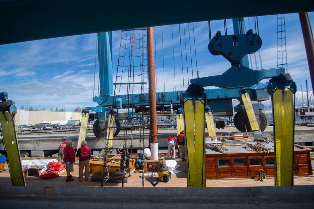 Crew members stand on the deck of the schooner Adventuress after it is lowered into the water Friday. (Jesse Major/Peninsula Daily News)