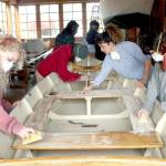 Students and instructors in the Real World Readiness program at the Northwest Maritime Center in Port Townsend sand with the grain on a wooden boat Wednesday. (Brian McLean/Peninsula Daily News)