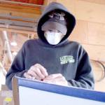 Caeleb Warwick works on the front of a wooden boat, manually sanding away the varnish Wednesday at the Northwest Maritime Center. (Brian McLean/Peninsula Daily News)