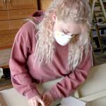 Briana Martin, part of the Real World Readiness program at the Northwest Maritime Center, uses sandpaper on a wooden boat Wednesday. (Brian McLean/Peninsula Daily News)