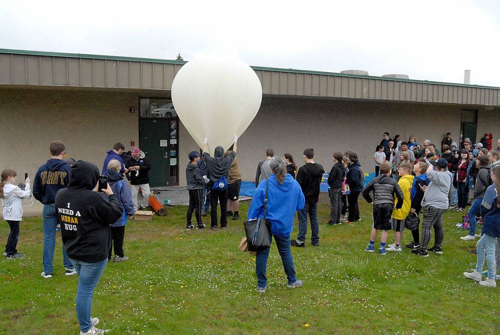 Student helpers hold a balloon as it is filled with helium Thursday at Port Angeles High School. (Keith Thorpe/Peninsula Daily News)