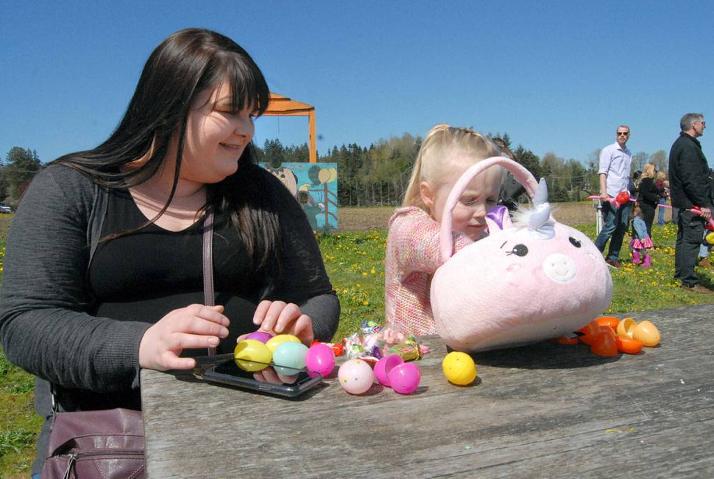 Amanda Critchfield of Sequim watches as her daughter, Amelia Critchfield, 5, looks through her basket of goodies after Saturdays hunt at the Pumpkin Patch near Sequim. (Keith Thorpe/Peninsula Daily News)