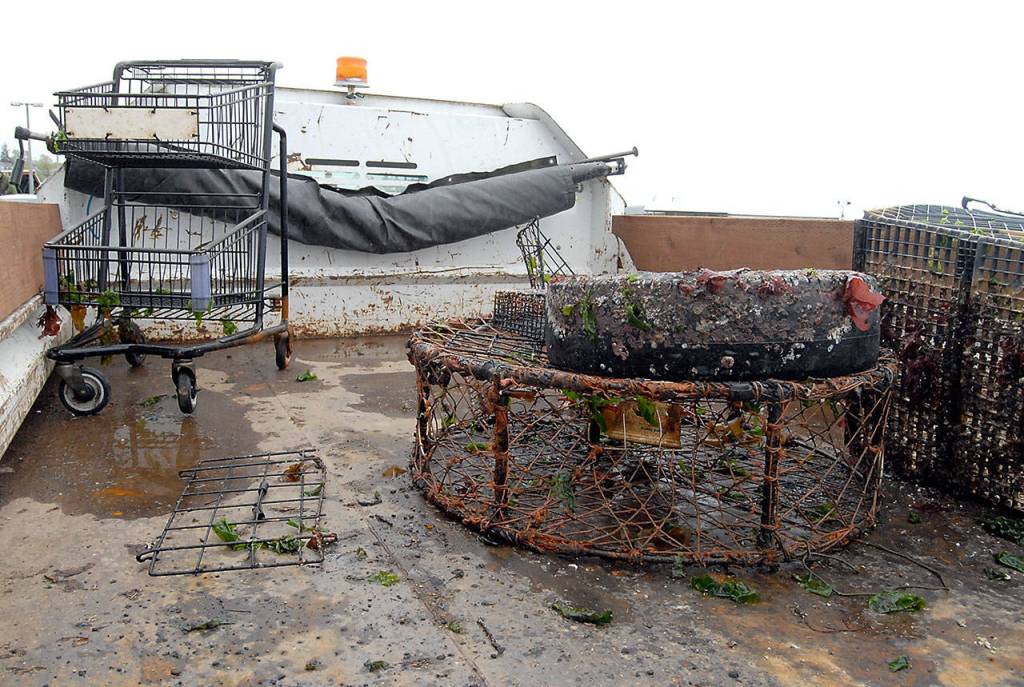 Shopping carts, derelict crab pots and a tire were among the debris pulled from beneath Port Angeles City Pier on Tuesday. (Keith Thorpe/Peninsula Daily News)