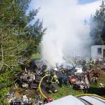 Firefighters work to extinguish a fire on Kacee Way near Port Angeles on Wednesday afternoon. (Jesse Major/Peninsula Daily News)
