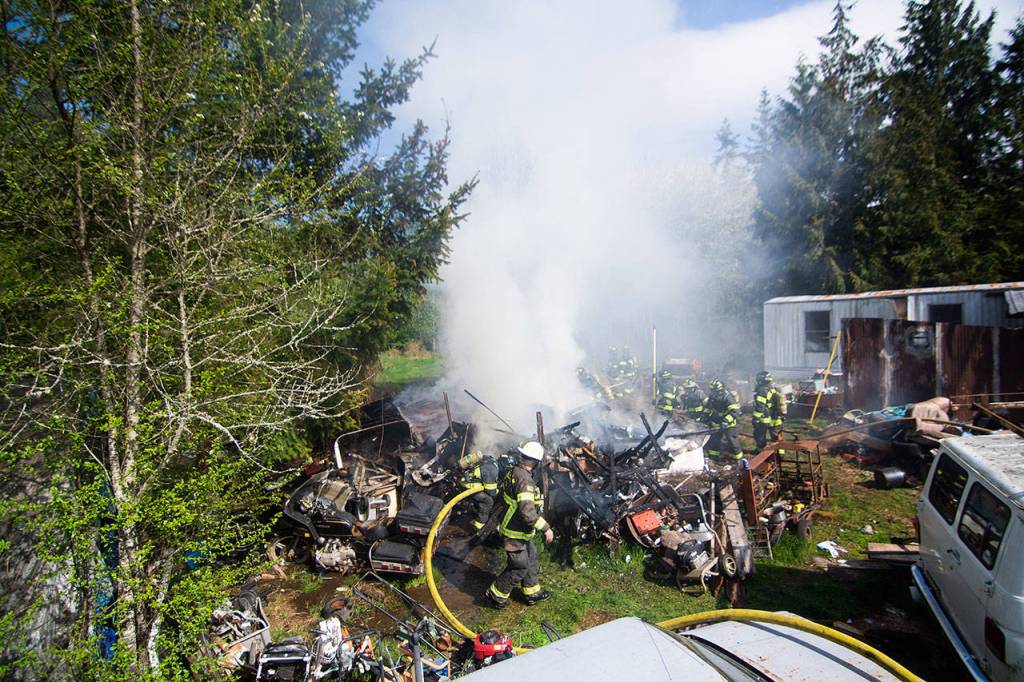 Firefighters work to extinguish a fire on Kacee Way near Port Angeles on Wednesday afternoon. (Jesse Major/Peninsula Daily News)