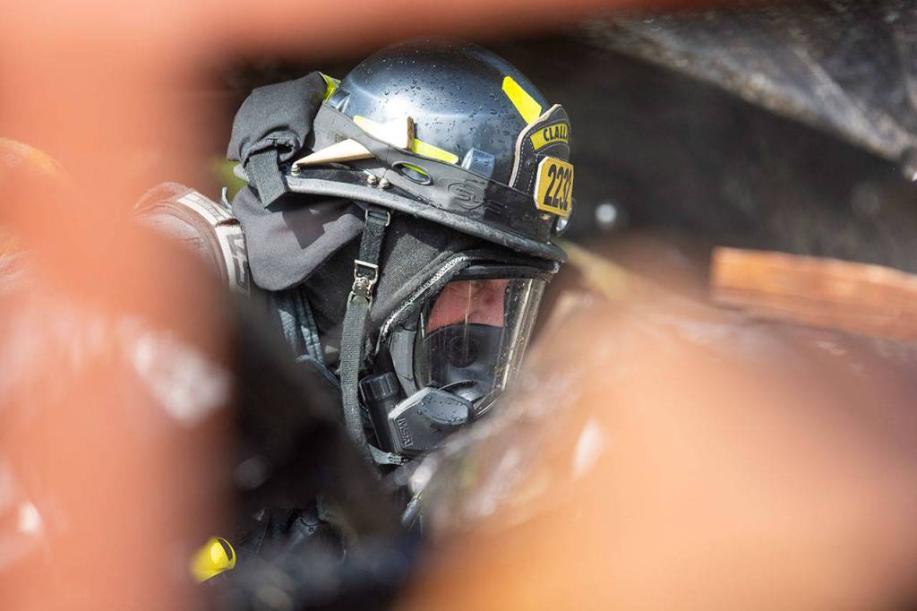 A firefighter with Clallam Fire District 2 works to put out a fire on Kacee Way on Wednesday afternoon. (Jesse Major/Peninsula Daily News)