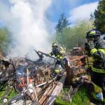 Firefighters work to extinguish a fire on Kacee Way near Port Angeles on Wednesday afternoon. (Jesse Major/Peninsula Daily News)
