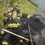 Andrew Pittman, a firefighter with Clallam Fire District 2, shifts through debris at a fire on Kacee Way west of Port Angeles on Wednesday afternoon. (Jesse Major/Peninsula Daily News)