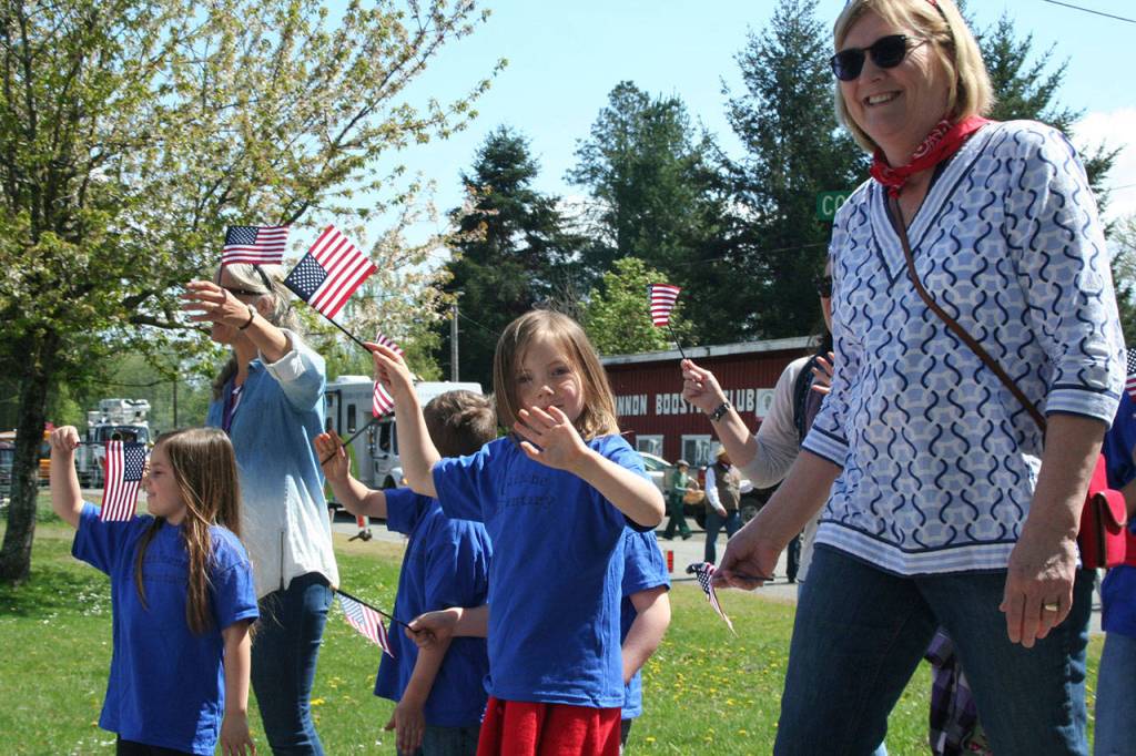 Quilcene Elementary students wave to the crowd toward the beginning of the Loyalty Day Parade route near the Brinnon Booster Club on Friday. (Brian McLean/Peninsula Daily News)