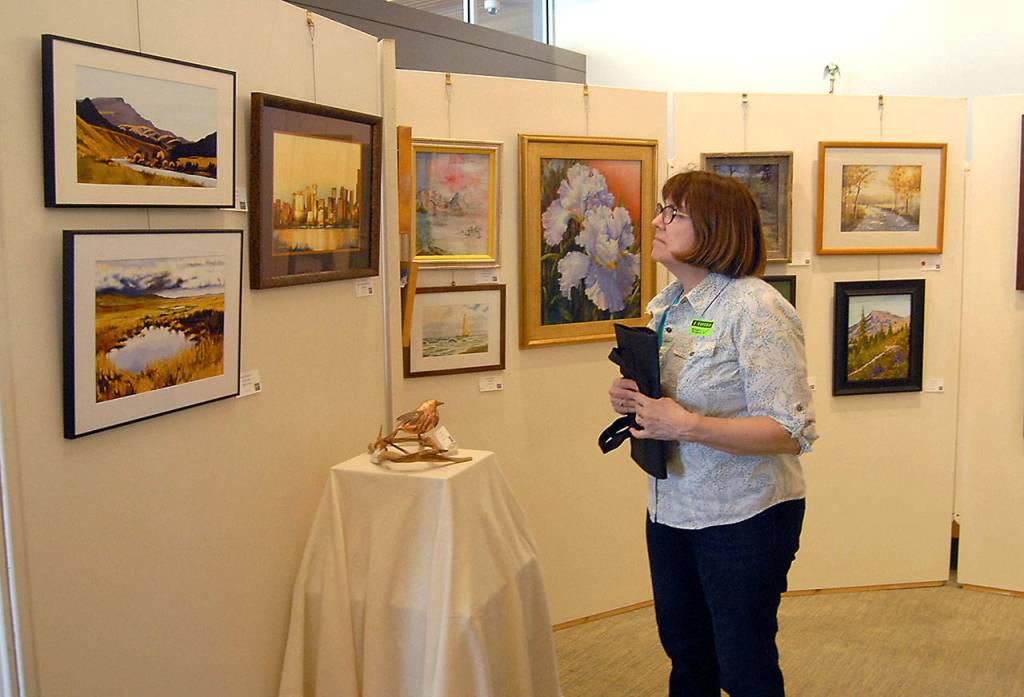 Gail Van Horsen of Sequim examines artworks on display at Sequim City Hall on Family Fun Day. (Keith Thorpe/Peninsula Daily News)
