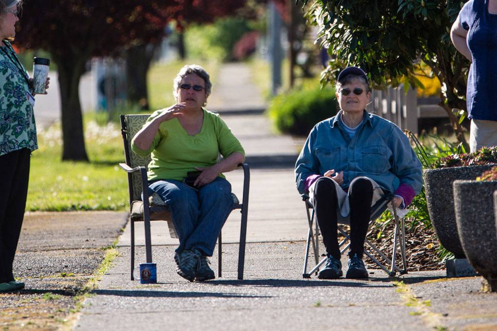 Candy Smith, left, and Susan Thompson watch as the Horizon Center moves down East Fifth Street on Thursday. (Jesse Major/Peninsula Daily News)