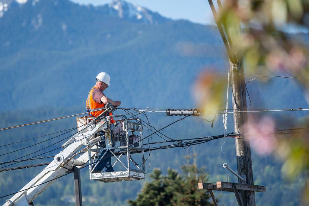 A lineman waits for the Horizon Center to pass on Thursday. Linemen lifted lines as the Horizon Center passed underneath. (Jesse Major/Peninsula Daily News)