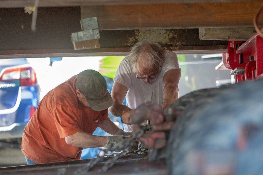 Jeff Monroe, right, works with another man under the Horizon Center as it prepares to turn onto Chase Street on Thursday. (Jesse Major/Peninsula Daily News)