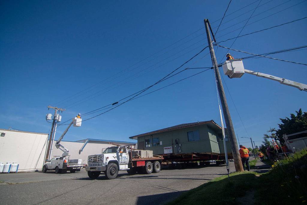 Linemen prepare to lift lines as the Horizon Center passes underneath. (Jesse Major/Peninsula Daily News)
