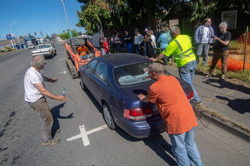 Crews use a frontloader to help move a car that was blocking the Horizon Centers path to its new home at 223 E. Eighth St. on Thursday. (Jesse Major/Peninsula Daily News)