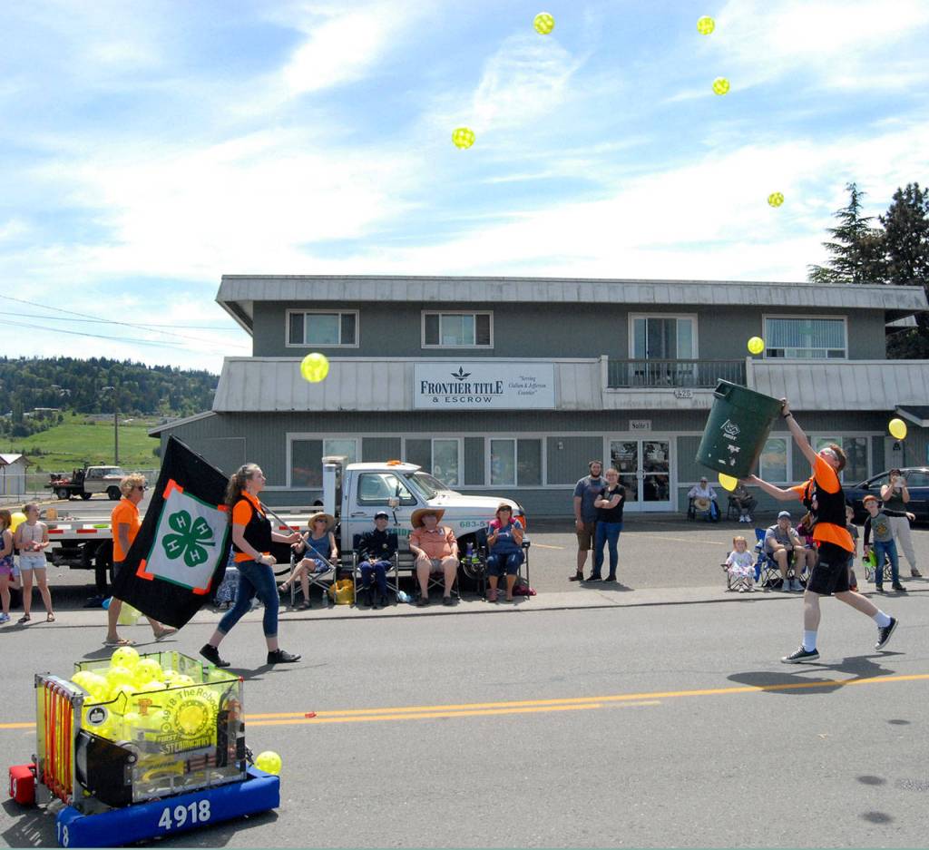 Max Morningstar, 17, a member of Sequim High Schools robotics team, right, catches a cascade of balls propelled from a remote controlled robot launcher, lower left. (Keith Thorpe/Peninsula Daily News)