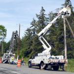 Jefferson County Public Utility District line crews install temporary poles along the north side of Flagler Road on Marrowstone Island on Wednesday in preparation for a new bridge to be built beginning mid-summer. The existing causeway at Kilisut Harbor is a barrier to fish migration and is being opened to allow migration and tidal land restoration. (Jeannie McMacken/Peninsula Daily News)