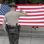 Clallam County Sheriffs Office Sgt. Brian Knutson, center, salutes a flag held by Sgt. John Keegan, left, and Deputy Don Kitchen during a memorial to fallen law enforcement officers on Friday at Veterans Park in Port Angeles. (Keith Thorpe/Peninsula Daily News)