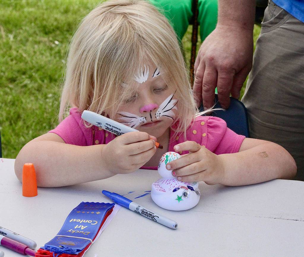 Olivia Phillips, age 4, turns a duck model into art at the Duck Derby at Lincoln Park on Sunday. (Dave Logan/for Peninsula Daily News)