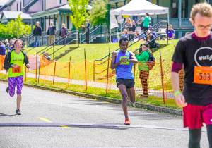 Taye Babeker Tirfea, from Addis Ababa, Ethiopa, stops his watch ase he crosses the line in 37:37 to win the Mens Elite 2019 Rhody Run at Fort Worden State Park on Sunday. (Steve Mullensky/for Peninsula Daily News)