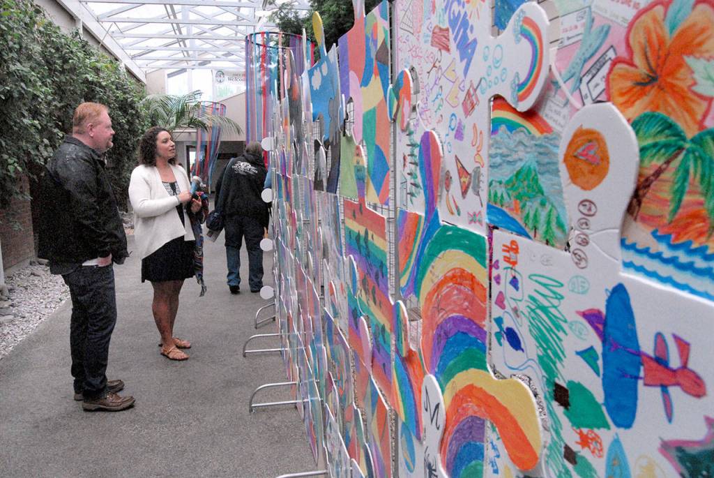 Dion Solheim of Graham and Ramona Valadez of Port Angeles examine a display of childrens art in the atrium of Vern Burton Community Center on Saturday.