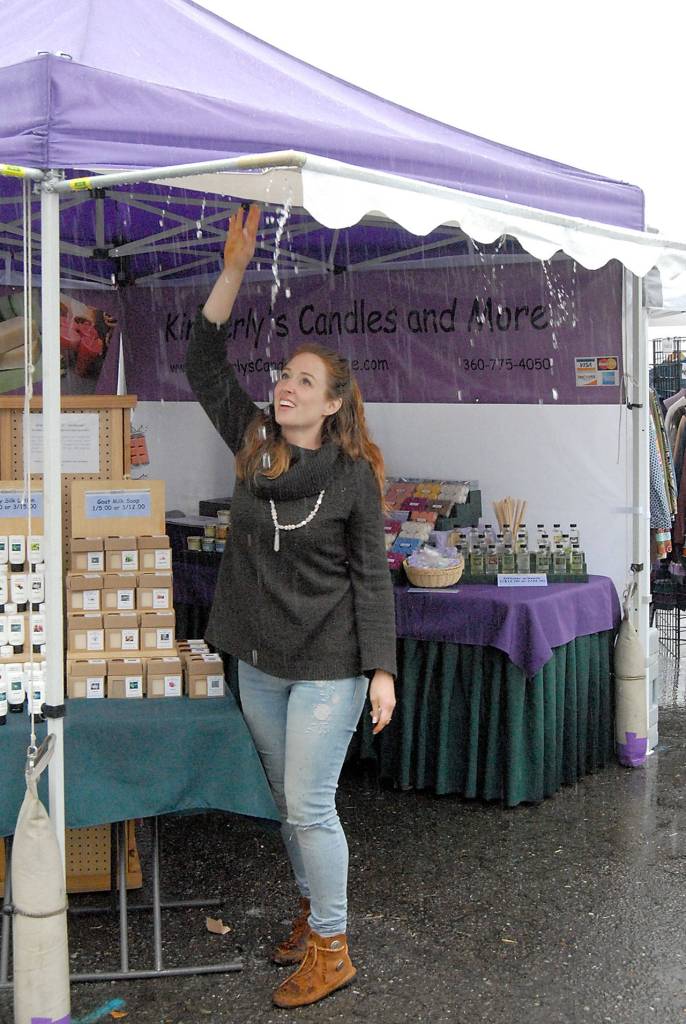 Jess Barnes of Bend, Ore.-based Loving Tree Henna drains pooled rainwater from fellow vendors tent next to her own after drenching rain moved over Port Angeles on Saturday, cancelling many outdoor performances and activities.