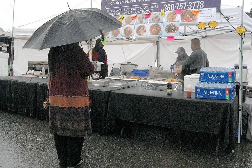 Renee Hasner of Lewiston, Idaho sands under her umbrella wating to place a food order from the Bancock Bistro food stand on Saturday.