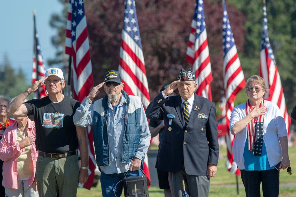 People salute and place their hands over their hearts as Amanda Bacon sings the Star Spangled Banner during the Memorial Day service at Mount Angeles Memorial Park in Port Angeles on Monday. (Jesse Major/Peninsula Daily News)