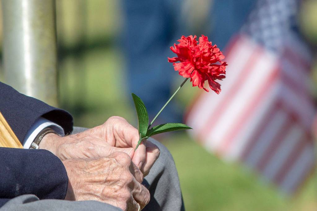 Veterans of Foreign Wars Post 1024 Officer of the Day Richard Smelling holds a flower during the annual Memorial Day service at Mount Angeles Memorial Park in Port Angeles on Monday. (Jesse Major/Peninsula Daily News)