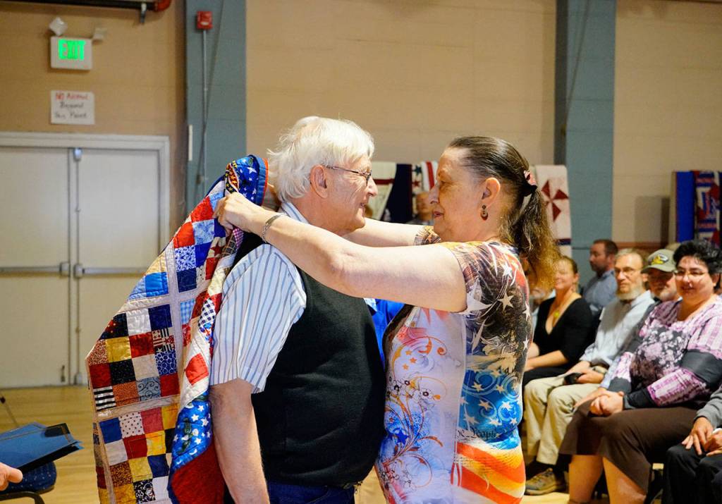 Henry Bernard of Chimacum receives a Quilt of Valor from Joellen Thompson during a Memorial Day program at American Legion Post 46 in Port Townsend on Monday. Bernard served 22 years in the Air Force and six years in the Marine Corps. Twenty-eight Quilts of Valor were presented during the program. (Steve Mullensky/for Peninsula Daily News)