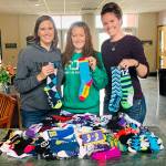 Port Angeles Marathon Association race Director Victoria Jones, center, with Caring for Kids co-founders, Jessica Johnson, right, and Jennifer Riffle, left. The marathon association donated more than $1,000 in socks to Caring for Kids.