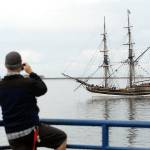 Keith Thorpe/Peninsula Daily News Christopher Thomsen of Port Angeles takes a cellphone photo of the tallship Lady Washington as it does a beauty pass of City Pier after arriving in Port Angeles on Thursday.