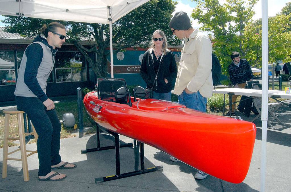 Troy Treaccar of Sound Bikes and Kayaks in Port Angeles discusses kayak features with Richelle and Mike Trippel of Tacoma on Saturday at Port Angeles City Pier. (Keith Thorpe/Peninsula Daily News)